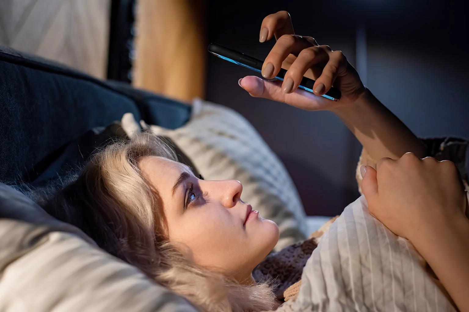 Young blonde girl is her smartphone bed trying fall asleep social addiction